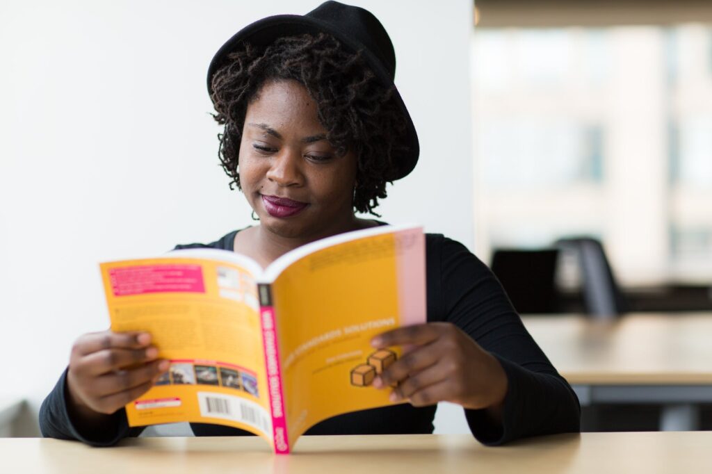 woman in black long sleeved shirt reading a yellow covered book