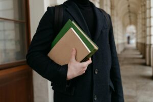 a person in black coat holding a green and brown book